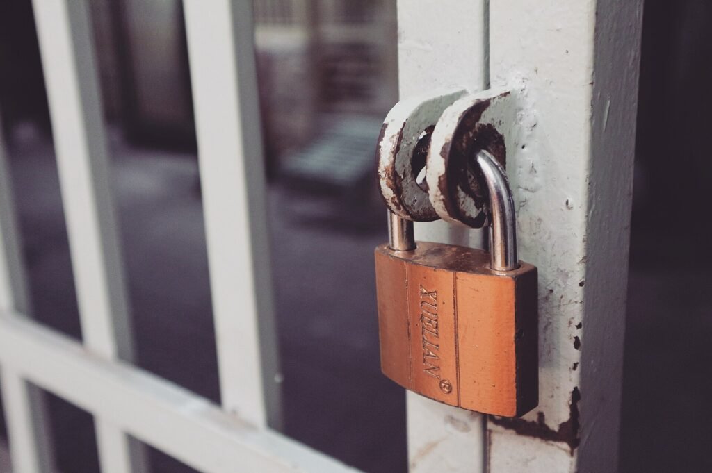 Brass padlock locking a white metal gate