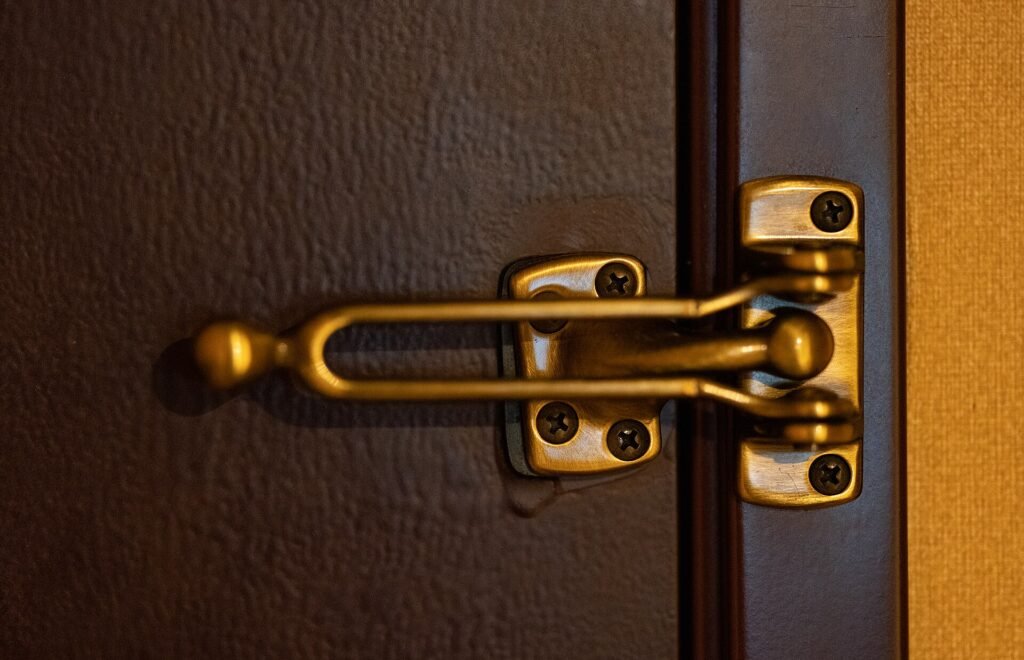 Brass deadbolt and door chain on the inside of a wooden door
